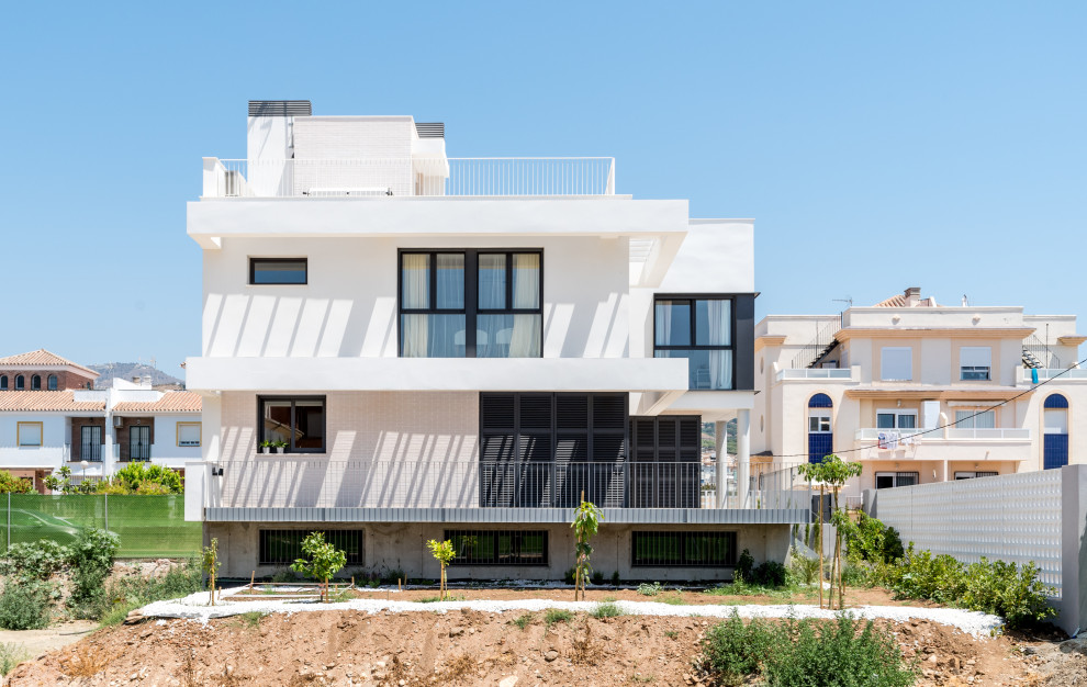 Mid-sized contemporary three-storey white house exterior in Madrid with mixed siding, a flat roof and a mixed roof.