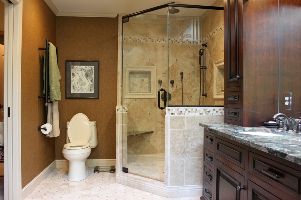 Design ideas for a mid-sized traditional master bathroom with raised-panel cabinets, dark wood cabinets, a corner shower, a two-piece toilet, beige tile, stone tile, brown walls, travertine floors, an undermount sink and granite benchtops.
