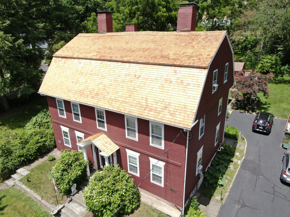 Foto på ett stort vintage rött hus, med tre eller fler plan, mansardtak och tak i shingel