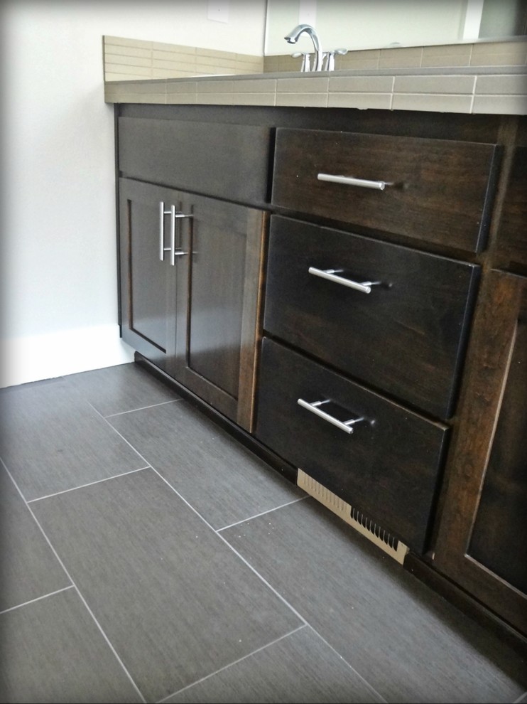 This is an example of a mid-sized contemporary master bathroom in Portland with shaker cabinets, dark wood cabinets, a freestanding tub, an alcove shower, beige tile, ceramic tile, tile benchtops, white walls, porcelain floors and a drop-in sink.
