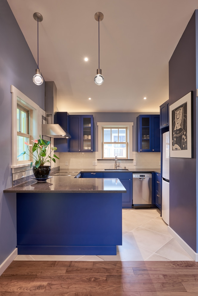 This is an example of a small transitional kitchen in Seattle with an undermount sink, flat-panel cabinets, blue cabinets, quartz benchtops, white splashback, subway tile splashback, stainless steel appliances, porcelain floors and blue benchtop.