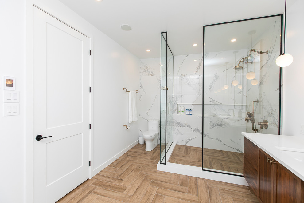 Large contemporary master bathroom in Ottawa with flat-panel cabinets, brown cabinets, a freestanding tub, a double shower, a one-piece toilet, white tile, ceramic tile, white walls, ceramic floors, a wall-mount sink, engineered quartz benchtops, brown floor, an open shower and white benchtops.