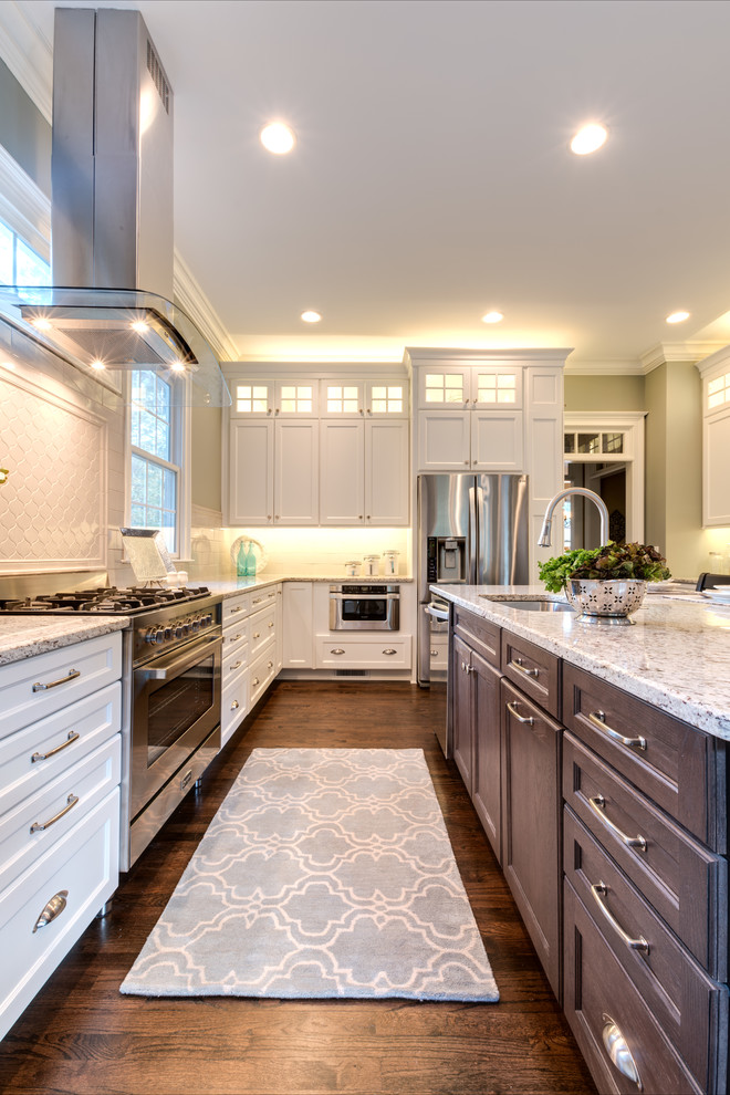This is an example of an expansive transitional l-shaped eat-in kitchen in Atlanta with an undermount sink, recessed-panel cabinets, white cabinets, granite benchtops, grey splashback, porcelain splashback, stainless steel appliances, dark hardwood floors, with island and white benchtop.