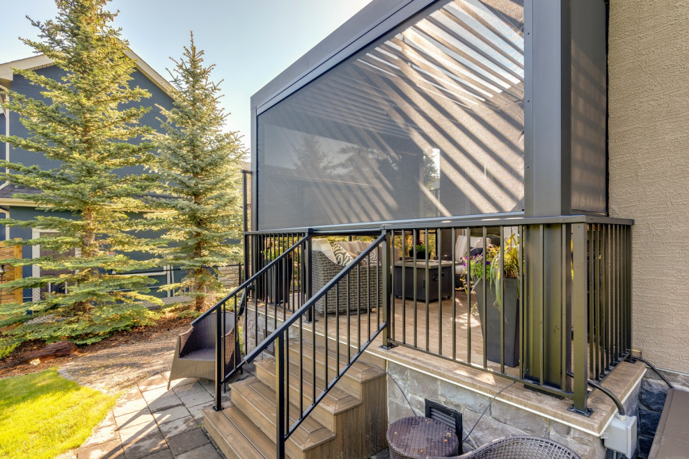 This is an example of a modern backyard deck in Calgary with a pergola.
