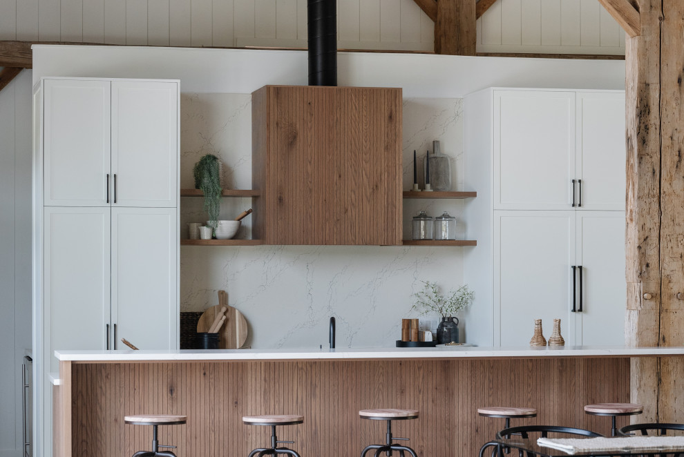 Example of a large transitional galley eat-in kitchen design with shaker cabinets, white cabinets, quartz countertops, white backsplash, quartz backsplash, paneled appliances, an island, white countertops and an undermount sink