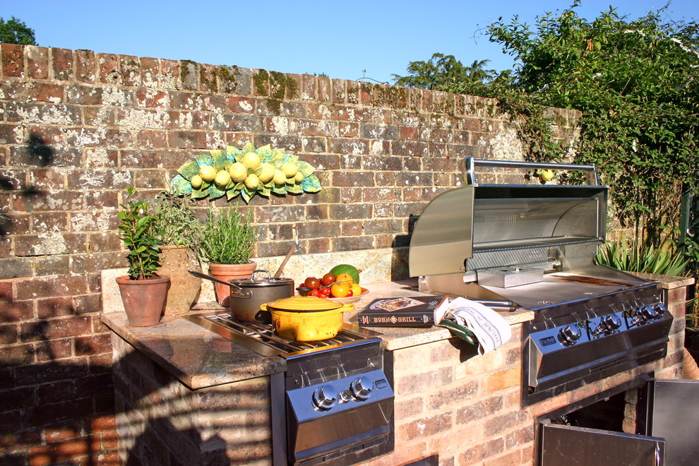 Photo of a small traditional courtyard patio in Kent with an outdoor kitchen, brick pavers and no cover.