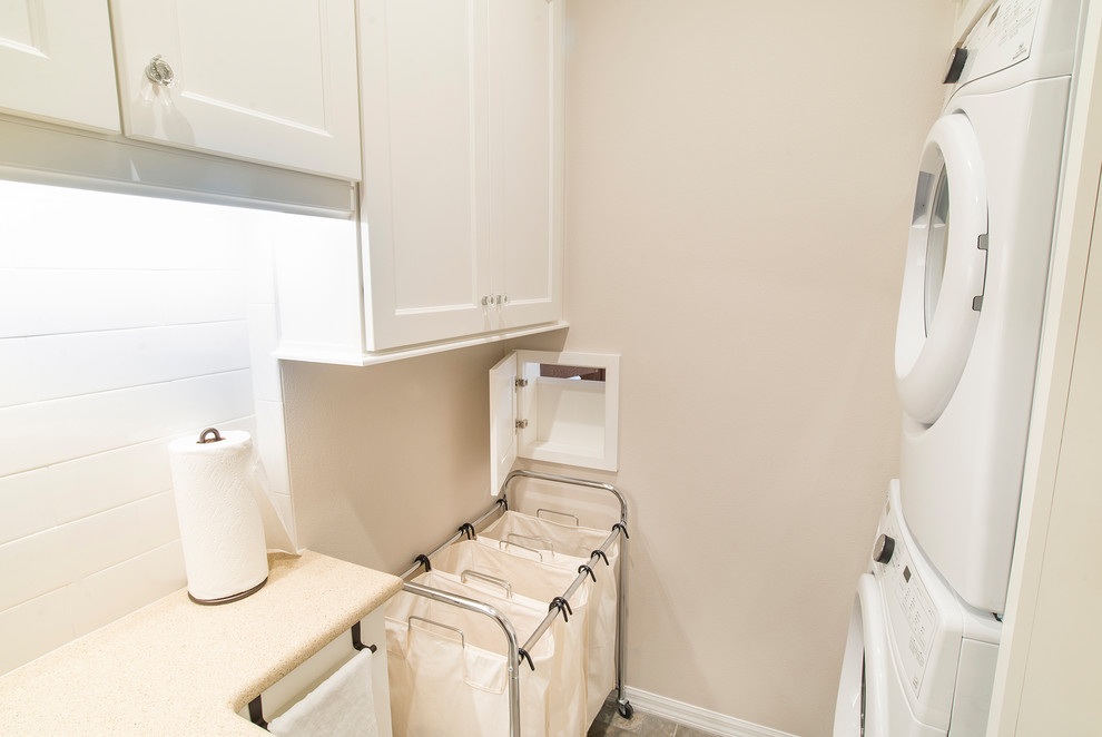 Inspiration for a small traditional galley dedicated laundry room in Orlando with an undermount sink, recessed-panel cabinets, white cabinets, laminate benchtops, white walls, a stacked washer and dryer and grey floor.