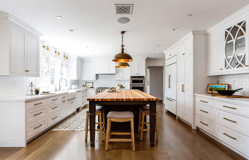 Photo of a mid-sized country l-shaped kitchen in Los Angeles with an undermount sink, shaker cabinets, beige cabinets, quartz benchtops, stainless steel appliances, medium hardwood floors and with island.