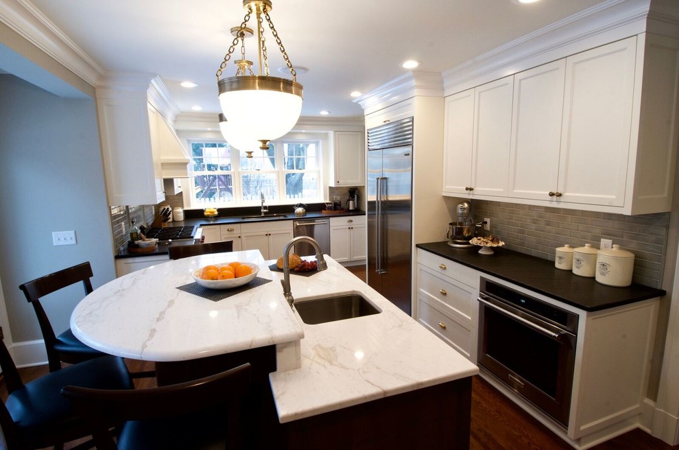 Large transitional u-shaped medium tone wood floor and brown floor kitchen photo in Minneapolis with an undermount sink, recessed-panel cabinets, white cabinets, quartz countertops, brown backsplash, glass tile backsplash, stainless steel appliances, an island and white countertops
