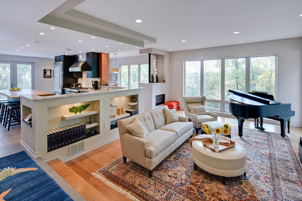 Photo of a mid-sized contemporary open concept living room in Detroit with a music area, light hardwood floors, a wall-mounted tv, white walls, a two-sided fireplace, a plaster fireplace surround and beige floor.