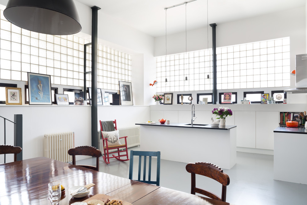 Inspiration for a large eclectic u-shaped eat-in kitchen in London with an undermount sink, flat-panel cabinets, white cabinets, solid surface benchtops, white splashback, cement tile splashback, stainless steel appliances, painted wood floors and with island.