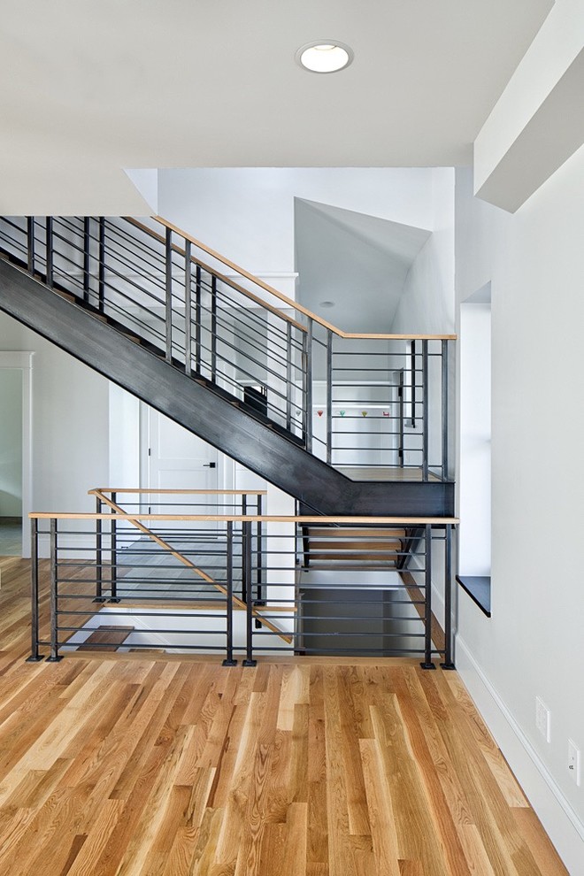 Mid-sized transitional wood l-shaped staircase in Denver with metal risers and metal railing.