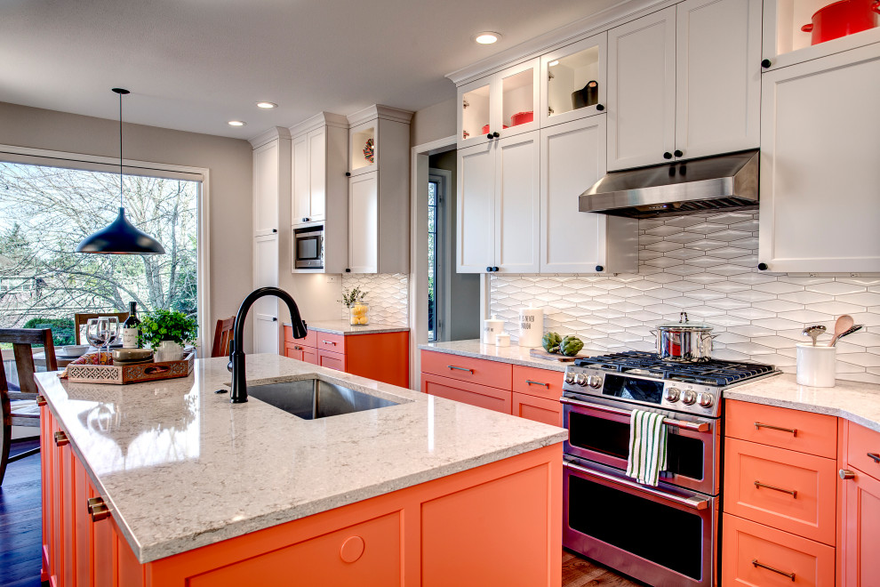 Inspiration for a transitional single-wall kitchen in Seattle with an undermount sink, shaker cabinets, orange cabinets, quartz benchtops, white splashback, ceramic splashback, stainless steel appliances, medium hardwood floors, with island, brown floor and grey benchtop.