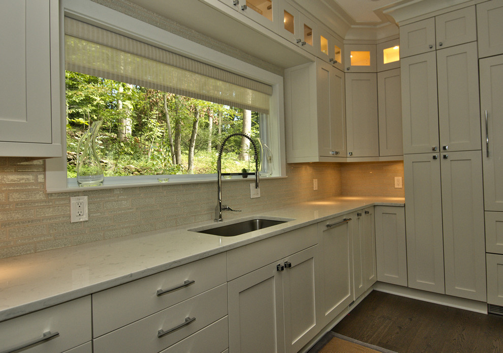 Mid-sized transitional l-shaped dark wood floor open concept kitchen photo in DC Metro with an undermount sink, shaker cabinets, white cabinets, quartz countertops, beige backsplash, porcelain backsplash, stainless steel appliances and an island