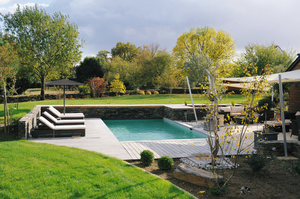 Design ideas for a mid-sized country backyard rectangular pool in Nantes with decking.