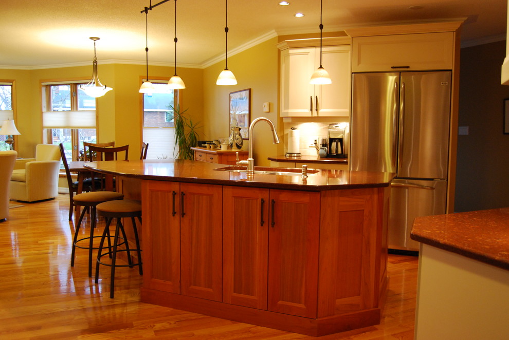 Photo of a transitional kitchen in Ottawa with an undermount sink, flat-panel cabinets, beige cabinets, quartz benchtops, beige splashback, porcelain splashback, stainless steel appliances, light hardwood floors and with island.