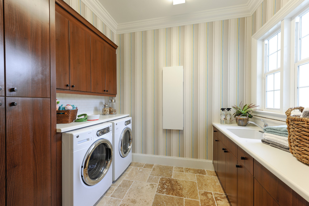 Design ideas for a large mediterranean galley dedicated laundry room in Miami with an undermount sink, flat-panel cabinets, dark wood cabinets, solid surface benchtops, multi-coloured walls, travertine floors and a side-by-side washer and dryer.