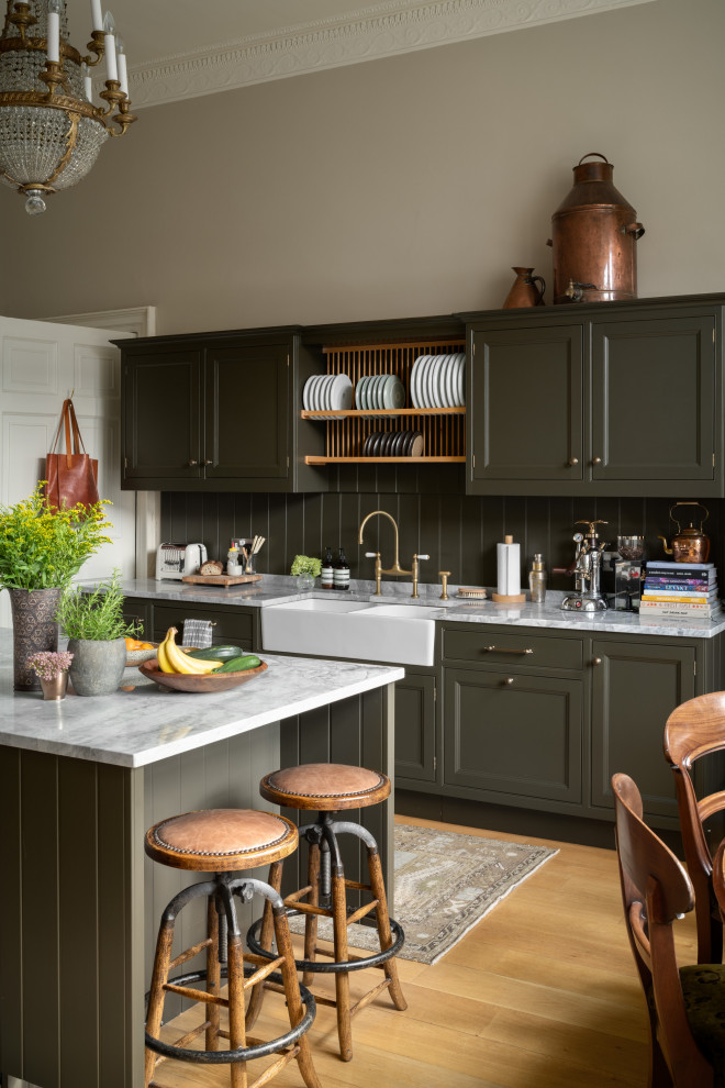This is an example of a mid-sized transitional galley kitchen in Edinburgh with a farmhouse sink, recessed-panel cabinets, green cabinets, green splashback, medium hardwood floors, with island, beige floor and white benchtop.