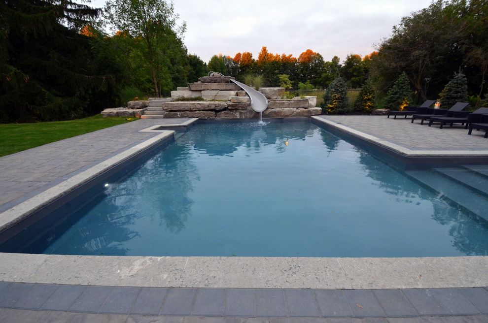 Design ideas for a mid-sized transitional backyard rectangular lap pool in Toronto with a water slide and brick pavers.
