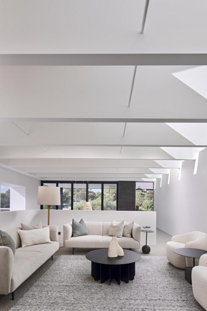 Imagen de salón abierto y abovedado contemporáneo con paredes blancas, suelo gris y vigas vistas