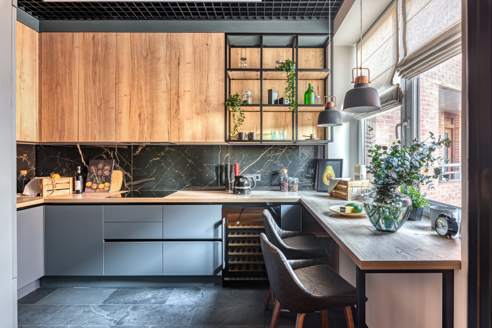 Photo of a mid-sized contemporary galley separate kitchen in Moscow with an undermount sink, flat-panel cabinets, black cabinets, wood benchtops, black splashback, porcelain splashback, black appliances, marble floors, with island and brown benchtop.