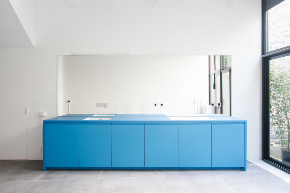 Foto di una cucina minimalista di medie dimensioni con lavello sottopiano, ante blu, top in superficie solida, paraspruzzi a specchio, elettrodomestici da incasso, pavimento con piastrelle in ceramica, pavimento grigio, top blu e travi a vista