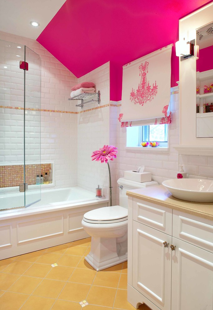 This is an example of a traditional kids bathroom in Montreal with a vessel sink, recessed-panel cabinets, white cabinets, an alcove tub, a shower/bathtub combo, a two-piece toilet, white tile, subway tile, pink walls and yellow floor.