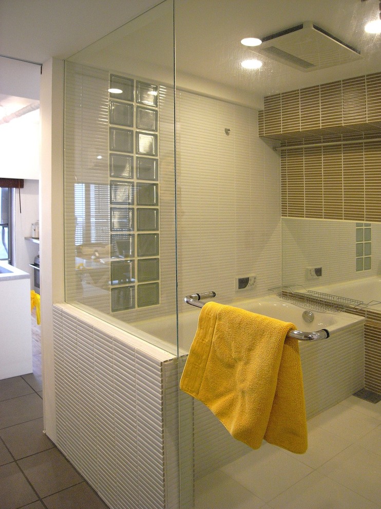 This is an example of a mid-sized asian master bathroom in Tokyo with a drop-in tub, white tile, glass tile, tile benchtops, brown walls and ceramic floors.