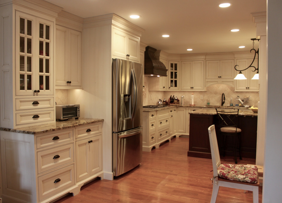 Inspiration for a large timeless medium tone wood floor kitchen remodel with beaded inset cabinets, granite countertops, beige backsplash, stone tile backsplash, stainless steel appliances and an island