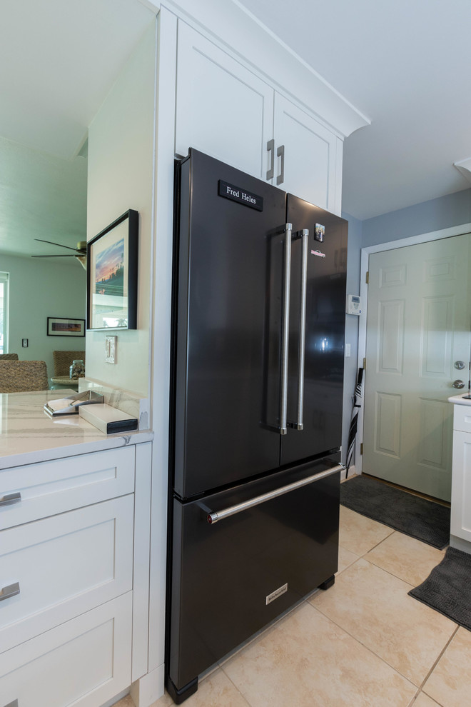 Open concept kitchen - mid-sized transitional galley ceramic tile open concept kitchen idea in Miami with a single-bowl sink, shaker cabinets, white cabinets, quartz countertops, black backsplash, glass tile backsplash, black appliances and a peninsula