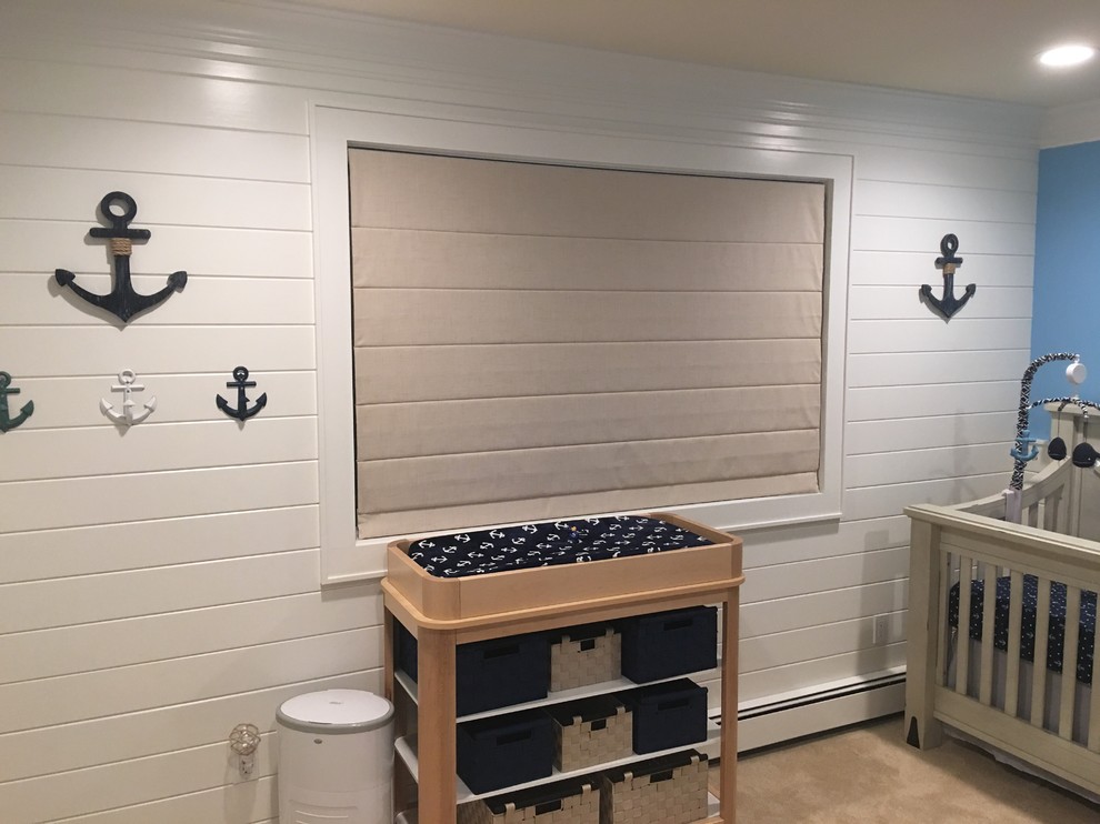 This is an example of a mid-sized beach style nursery for boys in New York with blue walls, carpet and beige floor.
