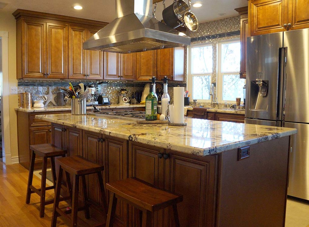 This is an example of a large beach style l-shaped separate kitchen in Orange County with a drop-in sink, flat-panel cabinets, medium wood cabinets, quartzite benchtops, stainless steel appliances, medium hardwood floors and with island.
