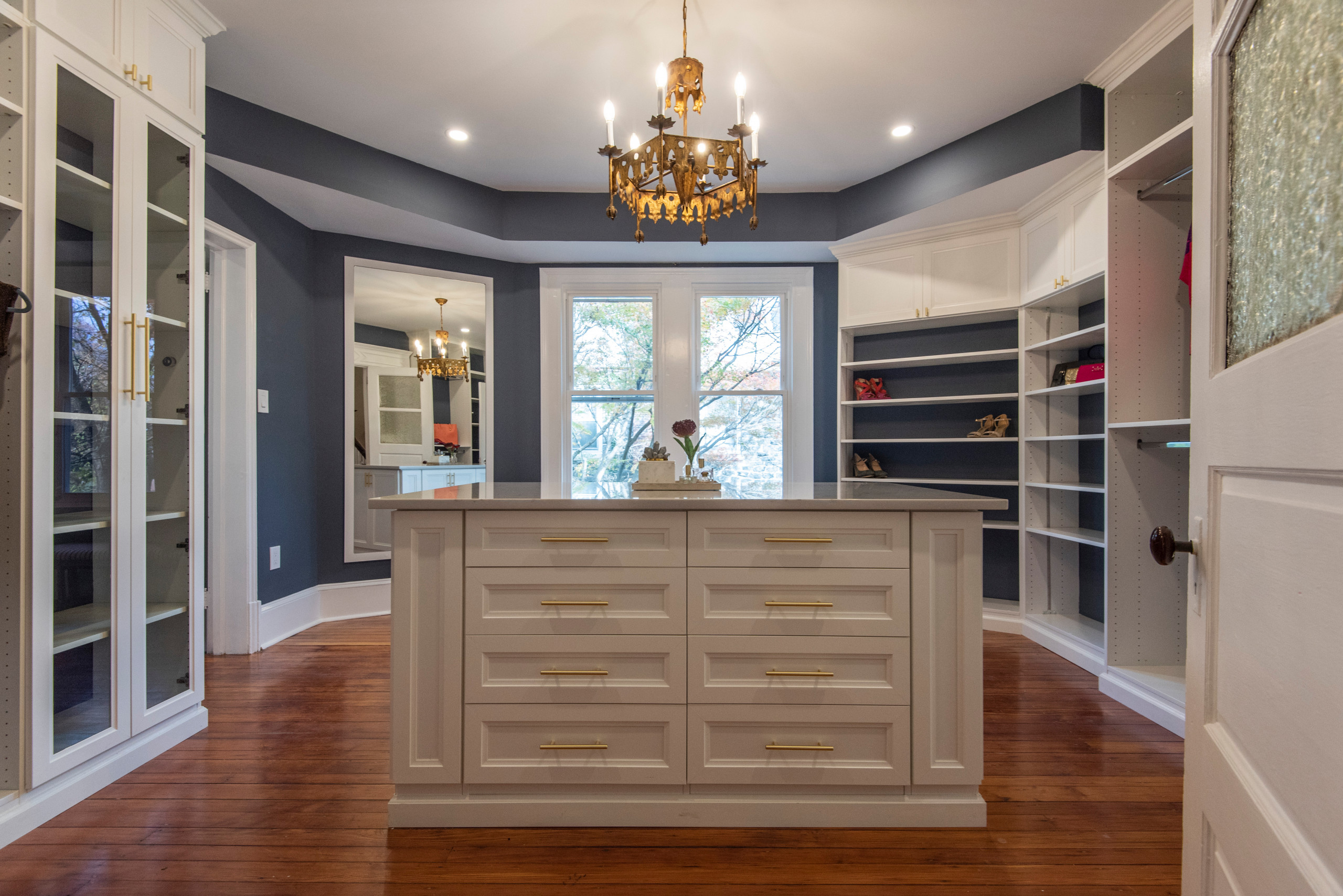 Beautiful Master Bedroom Closet renovation. Space now includes a Island with tons of drawers space. Cabinets with glass mullion doors to showcase your handbags. Adjustable shoe shelving with LED light