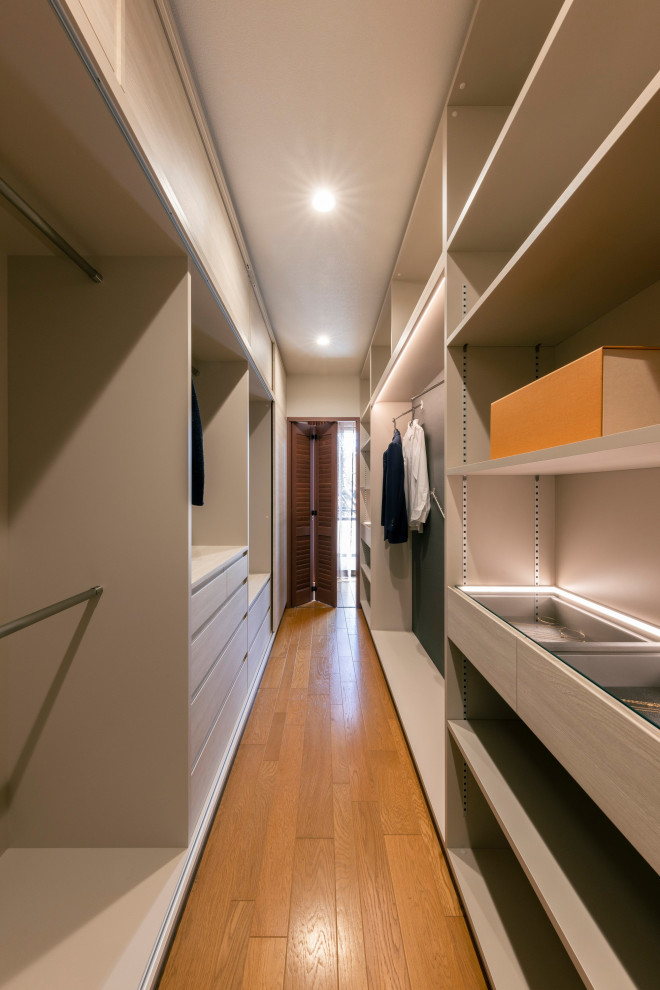 На фото: большая гардеробная комната унисекс в современном стиле с светлыми деревянными фасадами, паркетным полом среднего тона, оранжевым полом и потолком с обоями