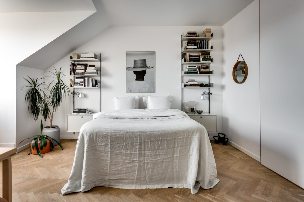 This is an example of a mid-sized scandinavian bedroom in Stockholm with light hardwood floors and white walls.