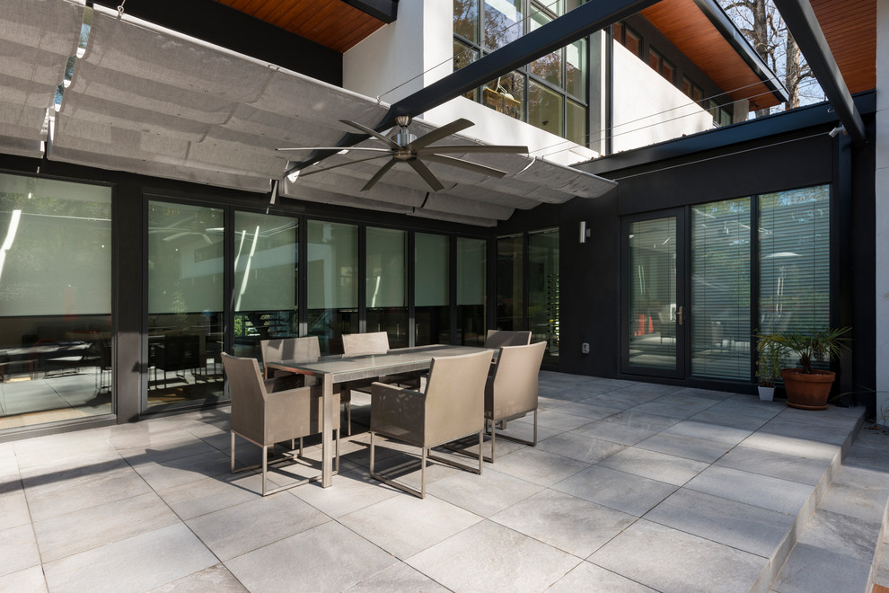 Example of a trendy backyard concrete paver patio design in Atlanta with an awning