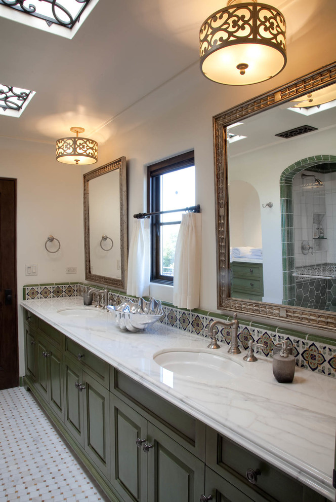 This is an example of a mid-sized mediterranean master bathroom in San Diego with raised-panel cabinets, green cabinets, an open shower, white tile, ceramic tile, white walls, ceramic floors, an undermount sink and marble benchtops.