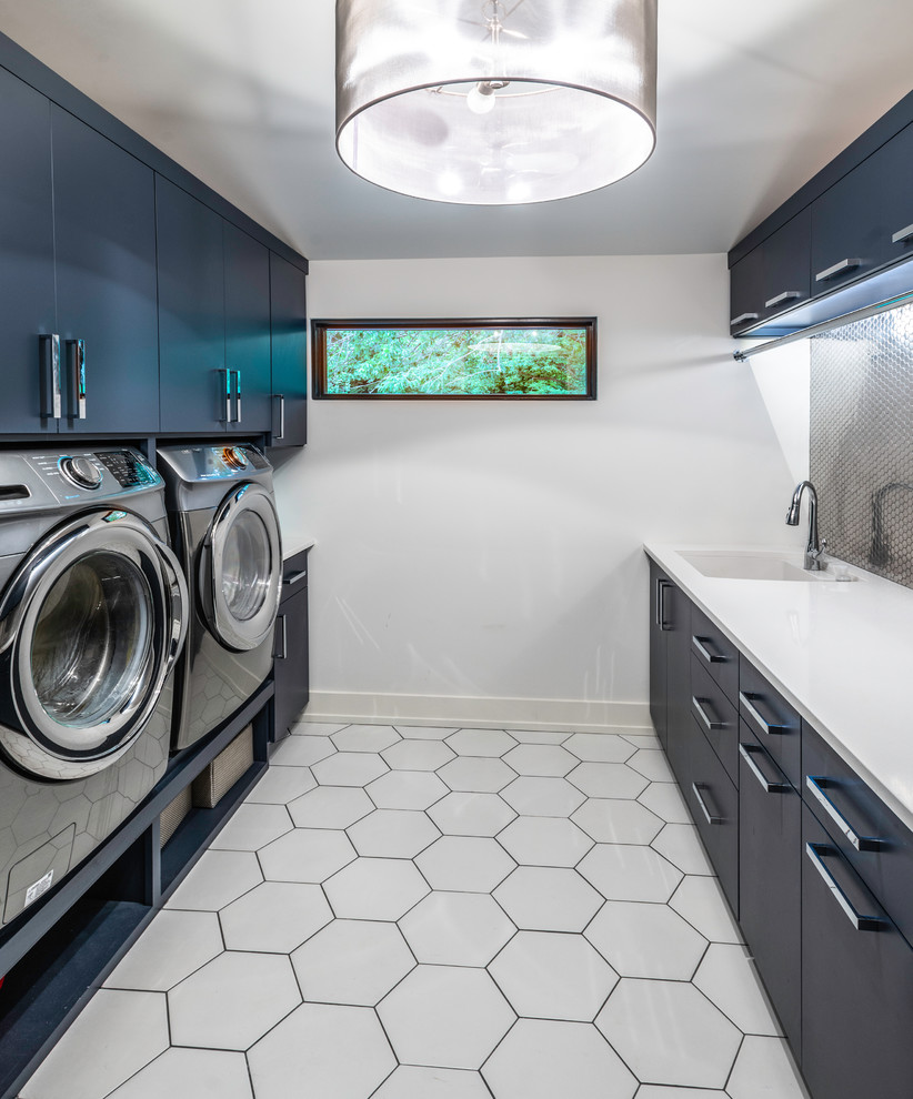 Photo of a contemporary galley laundry room in Nashville with an undermount sink, flat-panel cabinets, blue cabinets, white walls, white floor and white benchtop.
