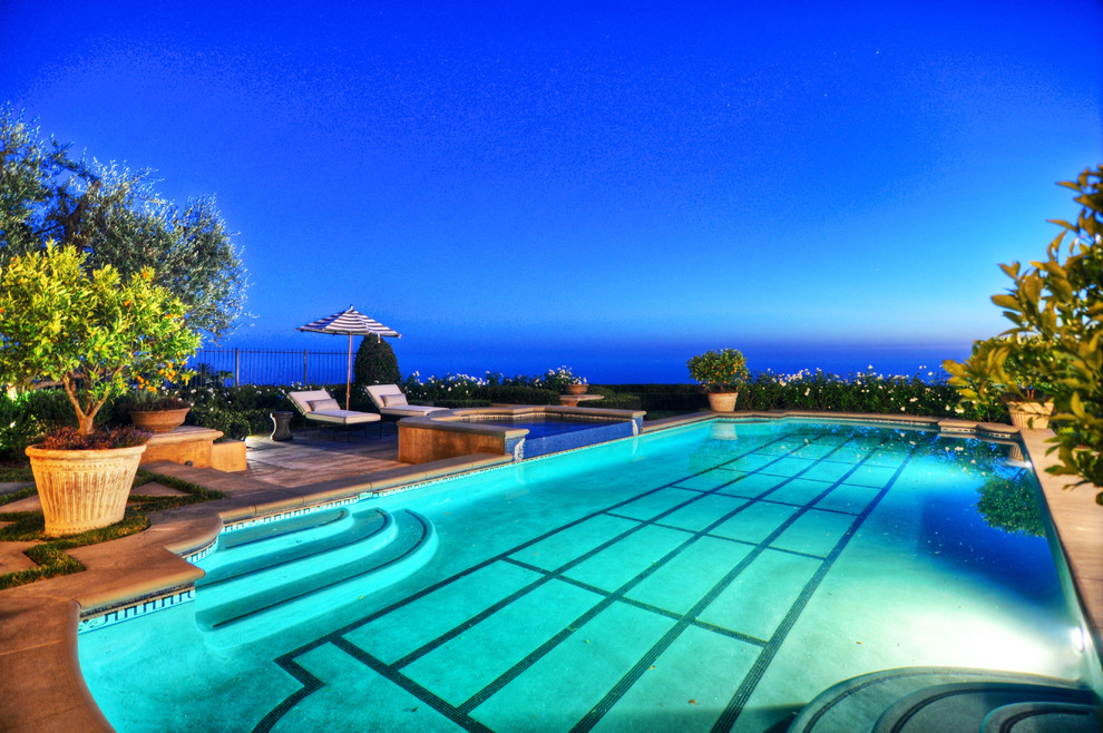 Inspiration for an expansive mediterranean backyard rectangular lap pool in Orange County with a pool house and tile.