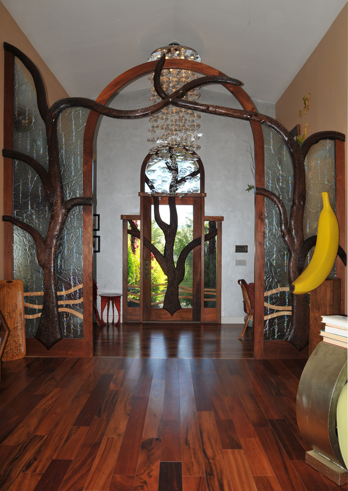 Large eclectic dark wood floor single front door photo with multicolored walls and a glass front door