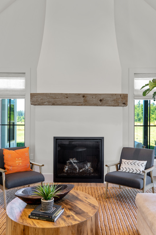 Design ideas for an expansive country open concept living room in Portland with a library, white walls, vinyl floors, a standard fireplace, a plaster fireplace surround, a freestanding tv, brown floor and exposed beam.