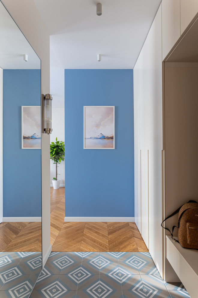 Bild på en funkis entré, med blå väggar och klinkergolv i porslin