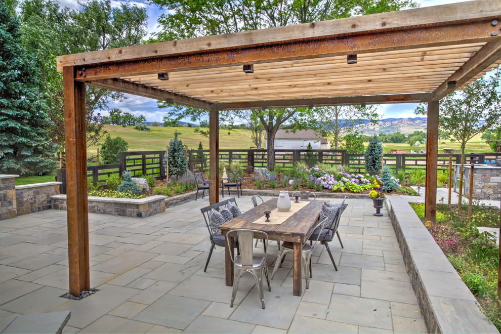 Photo of a large country back patio in Denver with a pergola and natural stone paving.