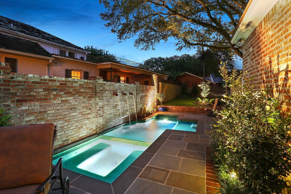 This is an example of a small traditional side yard rectangular pool in New Orleans with a hot tub and natural stone pavers.