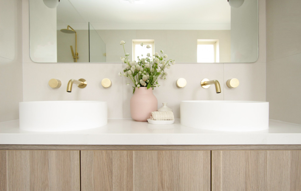Inredning av ett modernt mellanstort vit vitt en-suite badrum, med skåp i ljust trä, ett fristående badkar, en öppen dusch, en toalettstol med separat cisternkåpa, vit kakel, keramikplattor, klinkergolv i porslin, ett fristående handfat, bänkskiva i kvarts, grått golv och med dusch som är öppen