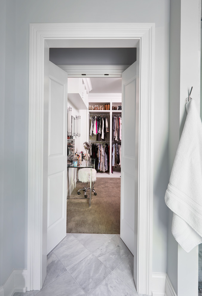 Inspiration for a mid-sized transitional gender-neutral dressing room in Nashville with raised-panel cabinets, white cabinets and grey floor.