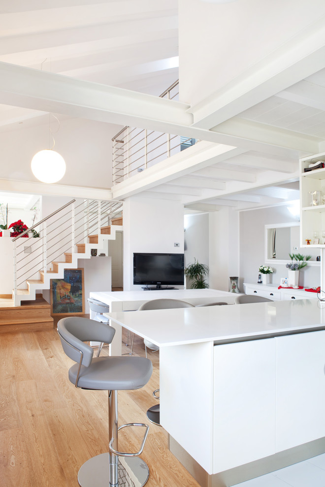 Photo of a contemporary kitchen in Bologna with flat-panel cabinets, white cabinets and light hardwood floors.