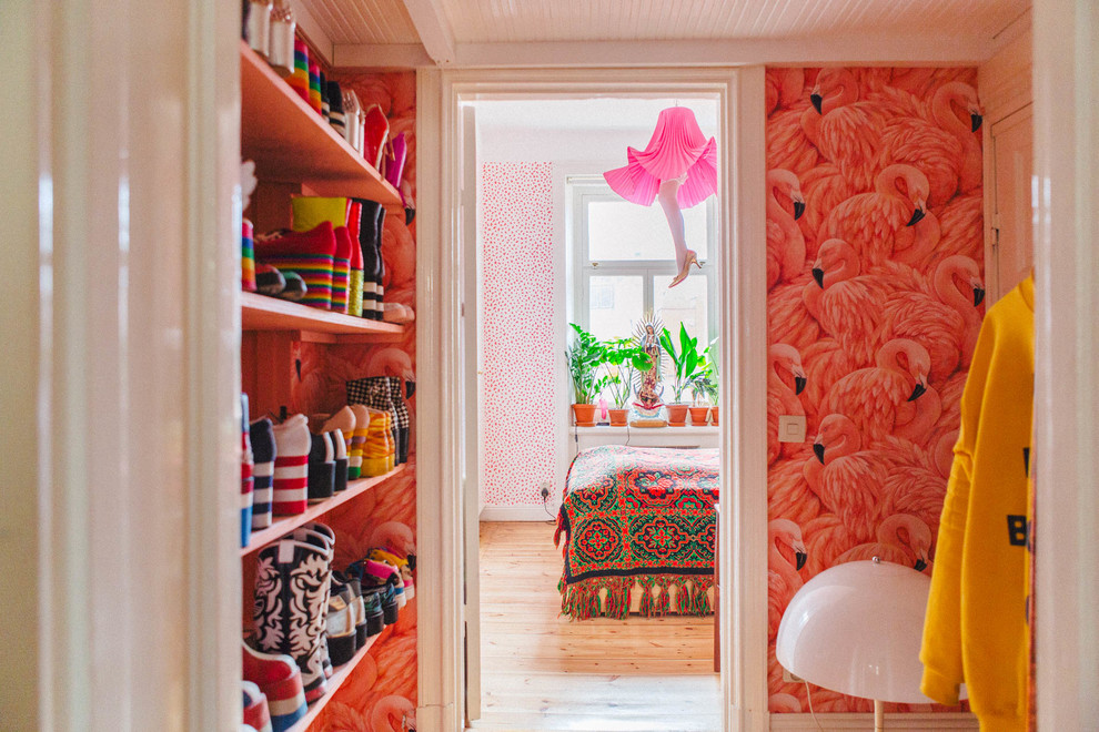 Eclectic gender-neutral walk-in wardrobe in Stockholm with open cabinets and light hardwood floors.