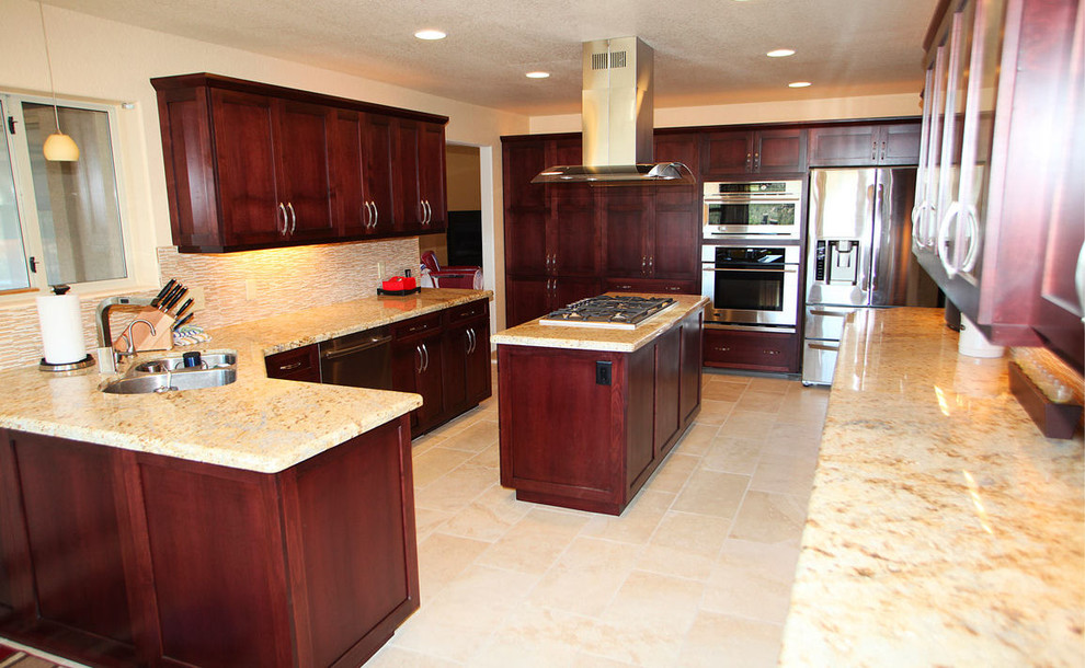 Example of a large transitional l-shaped eat-in kitchen design in Phoenix with shaker cabinets, dark wood cabinets, granite countertops, beige backsplash, glass tile backsplash, stainless steel appliances, an island and a double-bowl sink