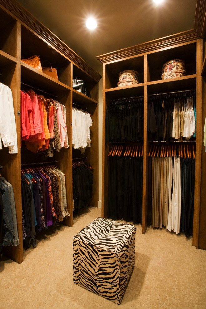 This is an example of a large traditional walk-in wardrobe in Dallas with raised-panel cabinets, medium wood cabinets and carpet.